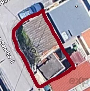 Aerial view of a house on a corner lot outlined in red; surrounding rooftops and street are visible.