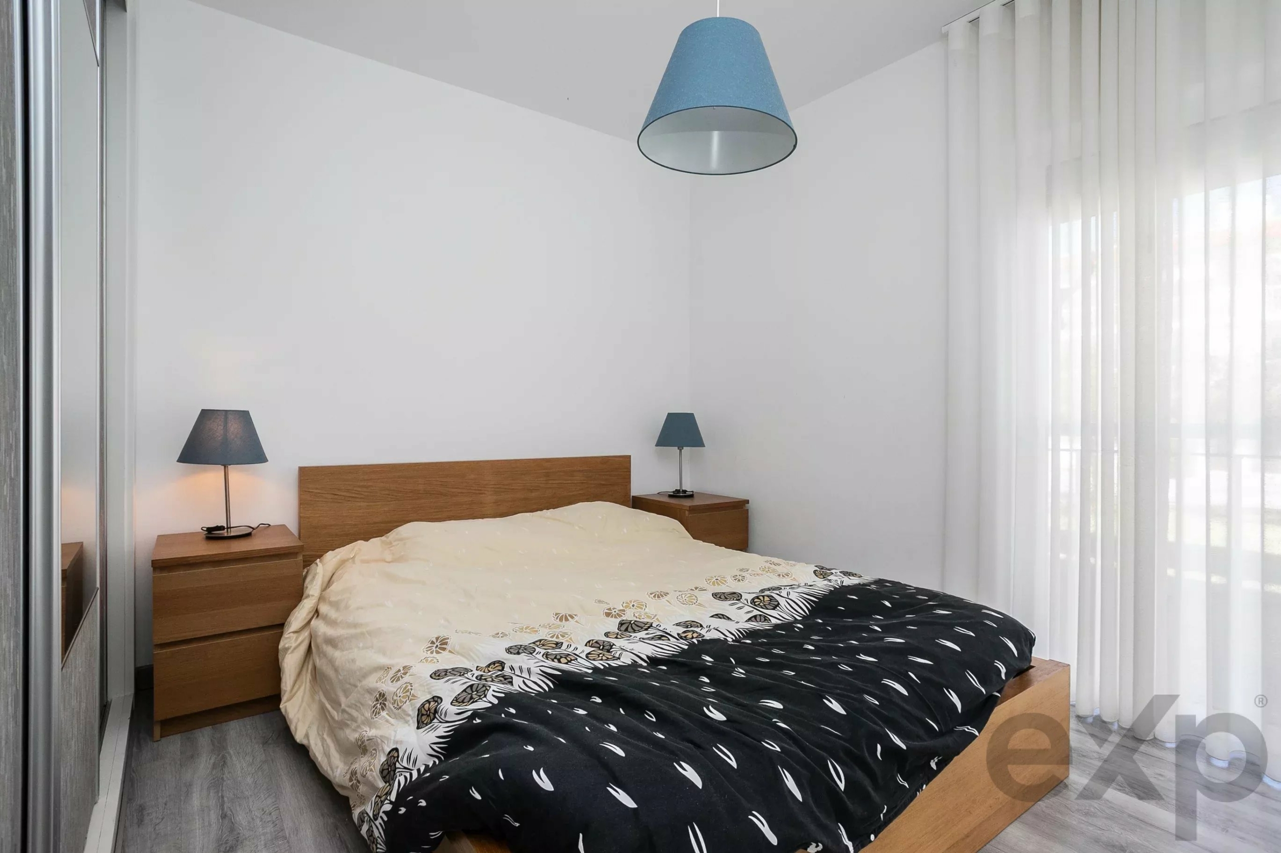 Contemporary bedroom with a wooden bed frame, two matching nightstands, and blue lamps on each side.