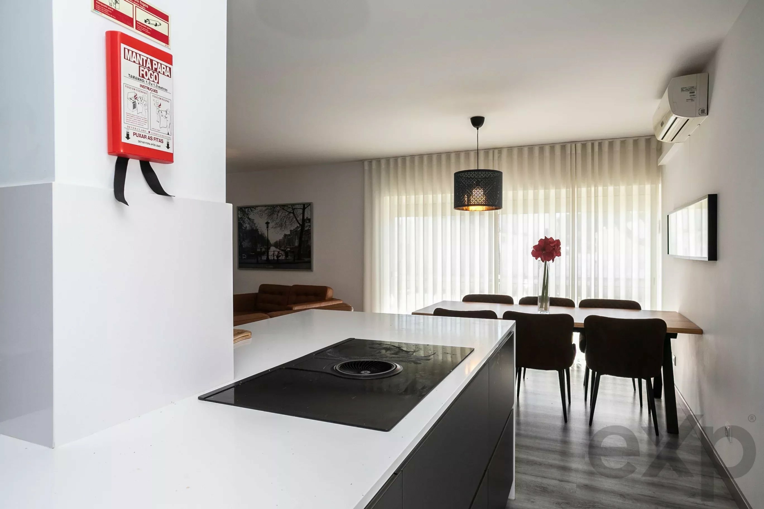 Red fire-extinguisher cabinet mounted on a white wall in a bright open-plan kitchen and dining area.