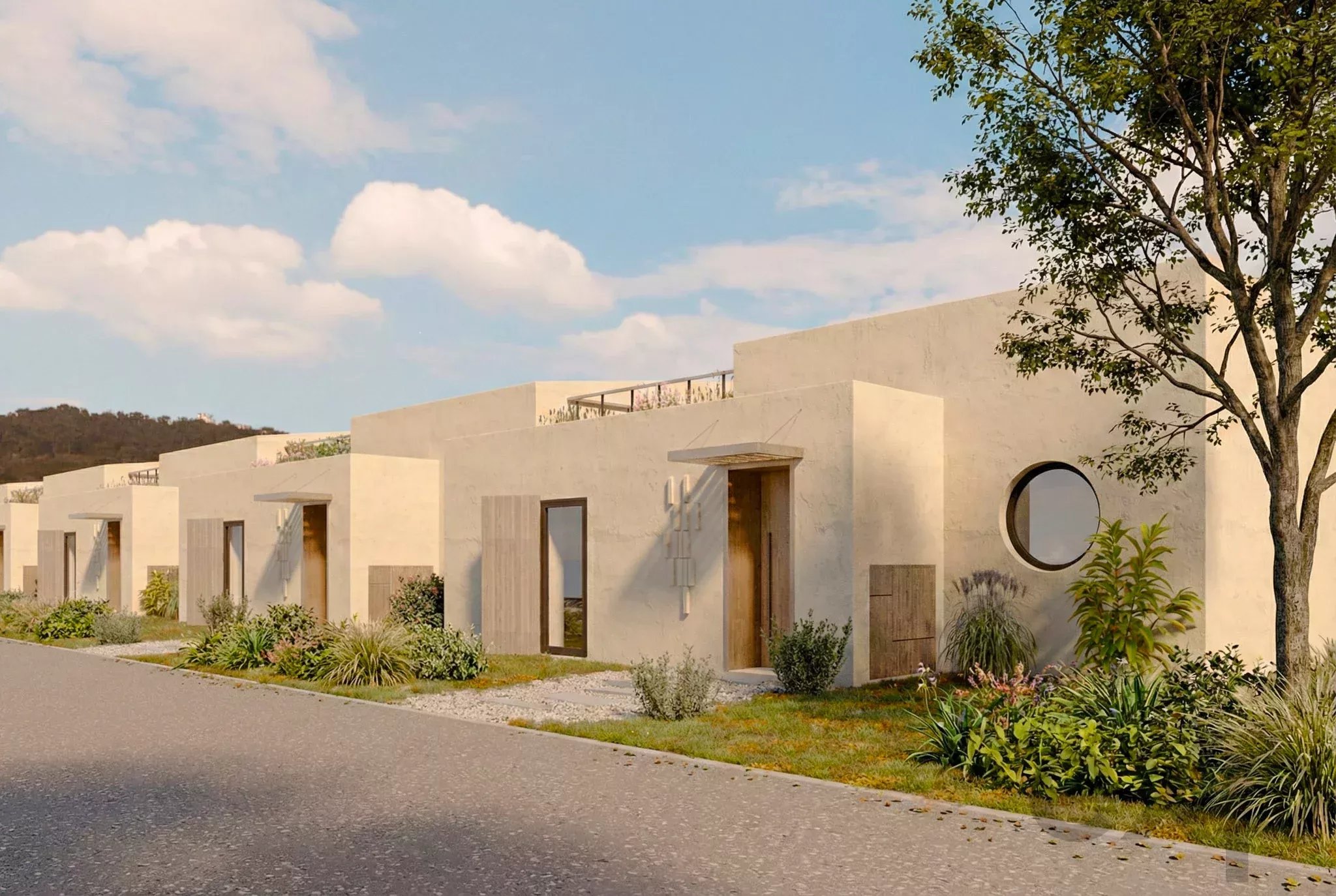 Row of light beige modern townhouses along a street, with a tree on the right and desert landscaping in front of each home.