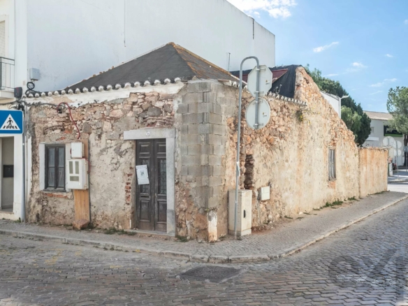 Old stone building on a cobblestone street with a pedestrian crossing sign nearby.