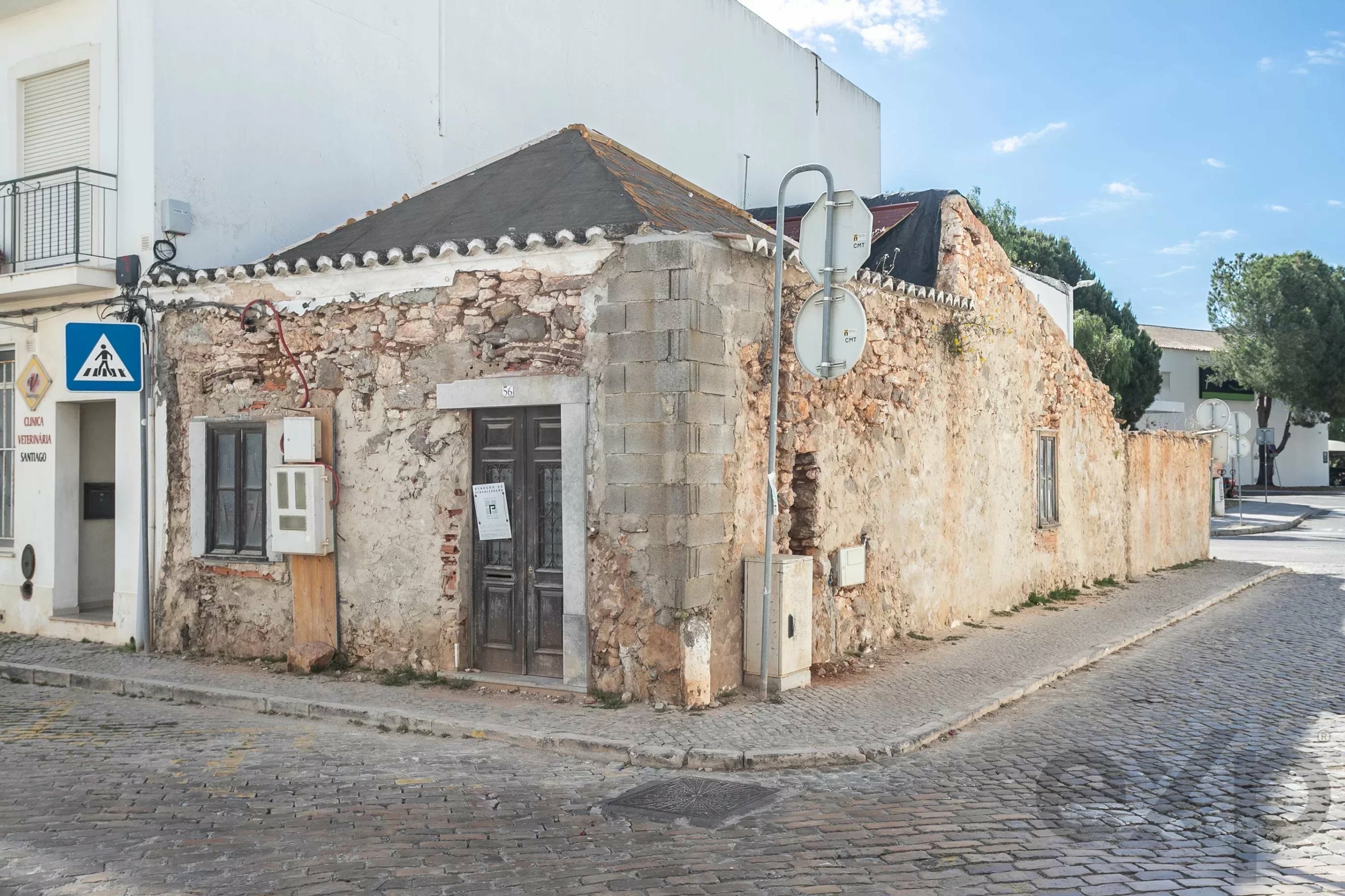 Old stone building on a cobblestone street with a pedestrian crossing sign nearby.