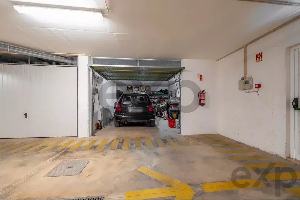 Black SUV parked in an open garage bay inside a dim, concrete parking level with yellow lines on the floor
