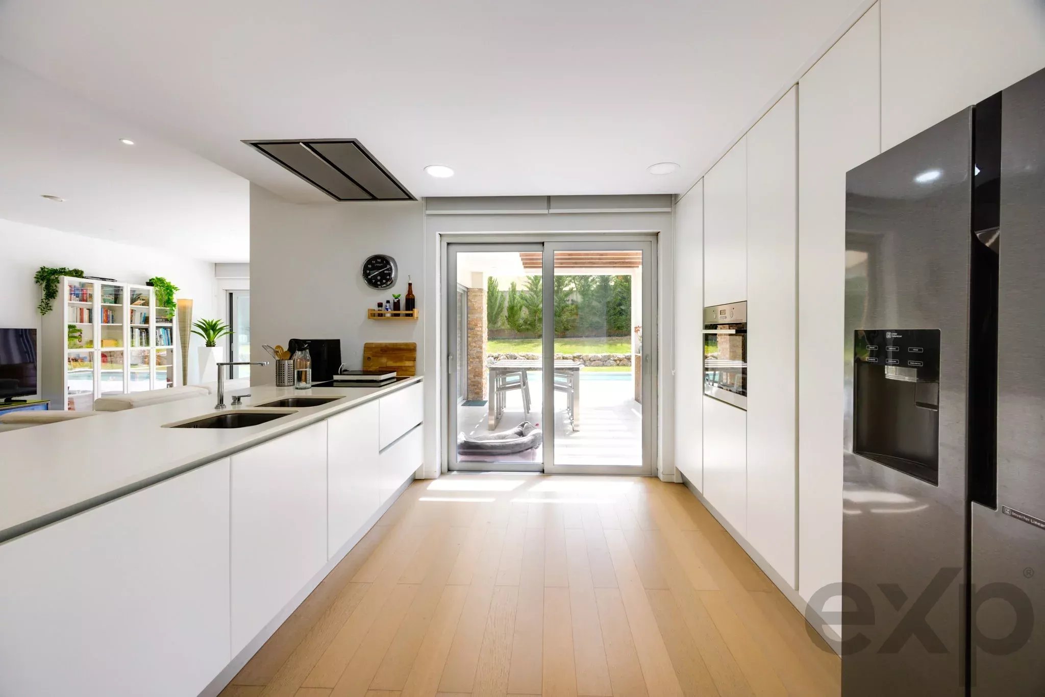 Bright modern kitchen with white cabinetry, a long island, and a glass sliding door opening to a patio.