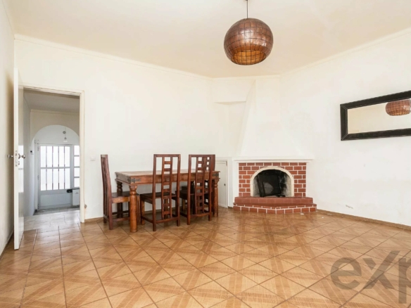 Dining room with a wooden table and tall chairs beside a brick fireplace and a round copper pendant light above.