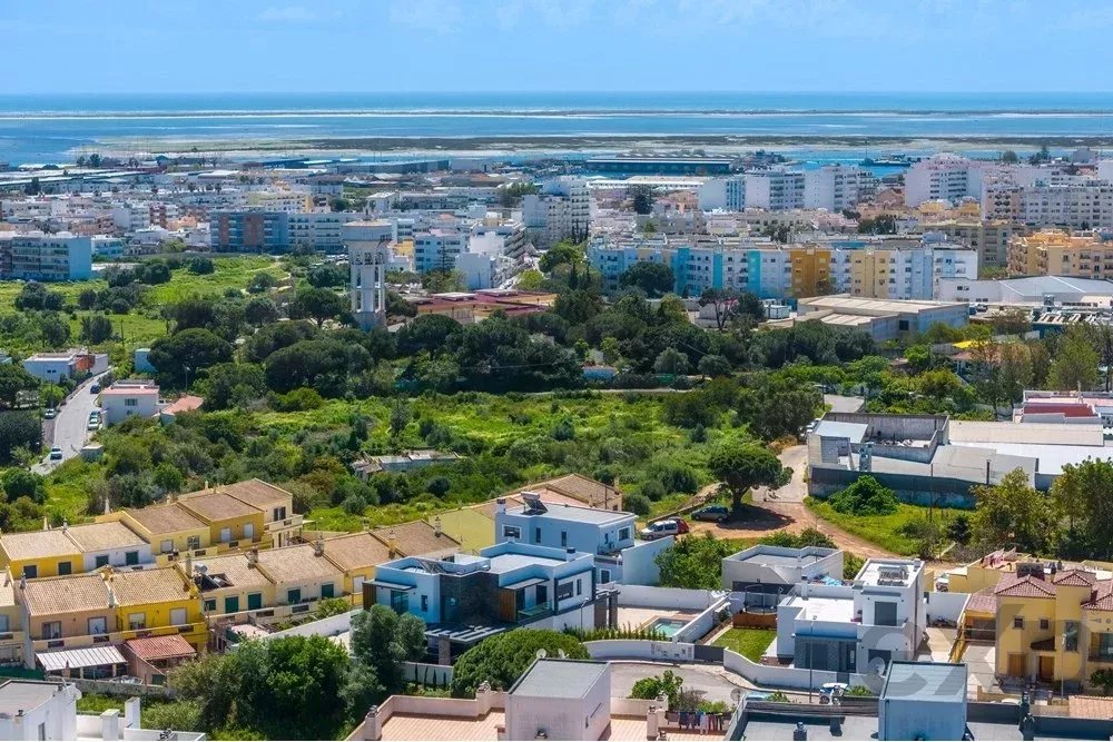 Aerial view of a seaside town with colorful apartment blocks, green parks, and a blue ocean in the distance?