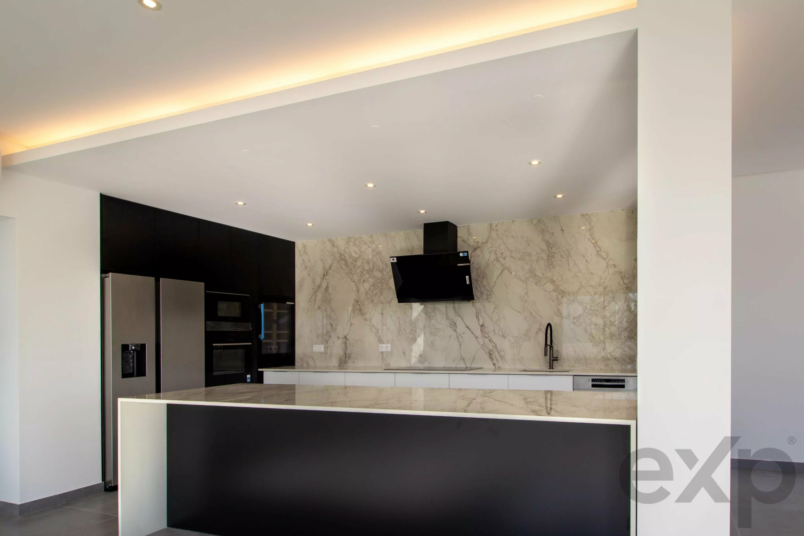 Contemporary kitchen with black cabinets, marble backsplash, and stainless appliances in an open layout.