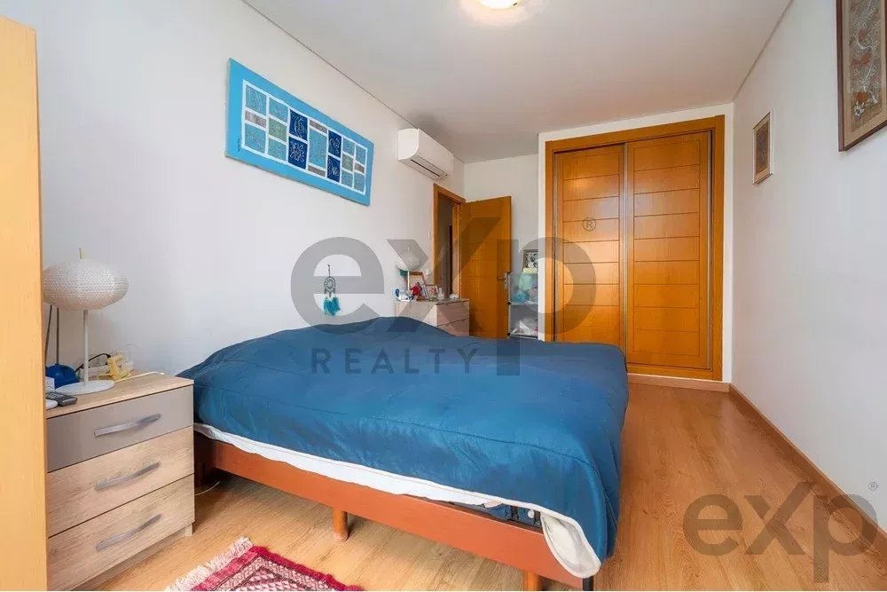 Bird's-eye view of a small bedroom with a blue bedspread, wooden nightstand, dresser, and a double wooden closet door.