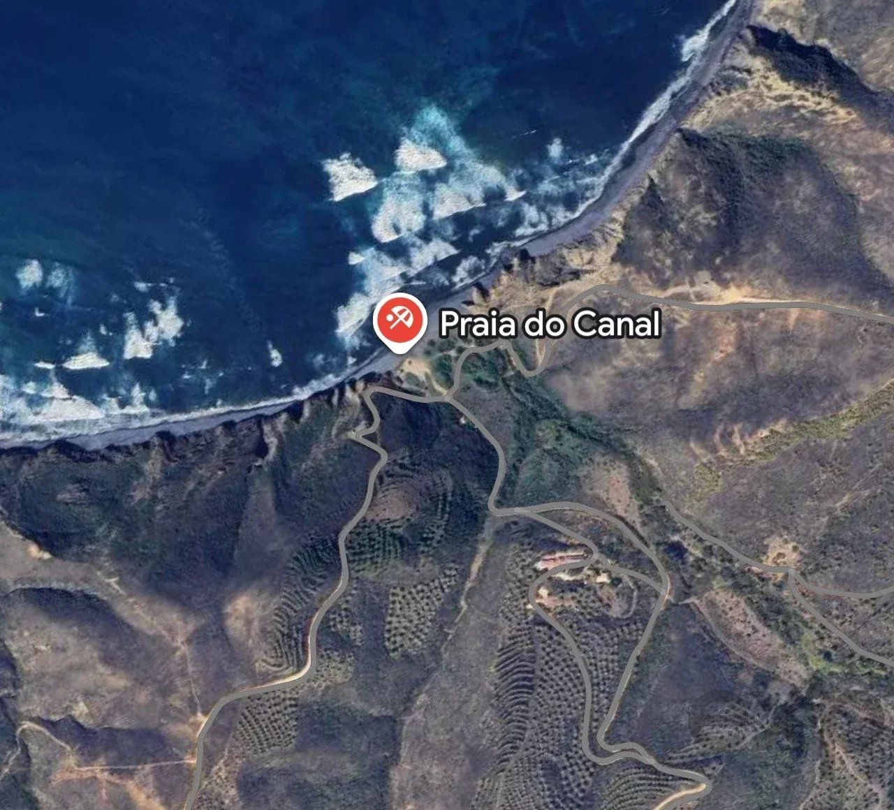 Aerial map of Praia do Canal showing a rocky coastline, blue sea, and winding roads along the shore.