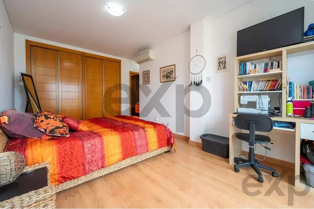 Bedroom with a red-orange striped bedspread, wooden wardrobes, and a study desk with shelves nearby