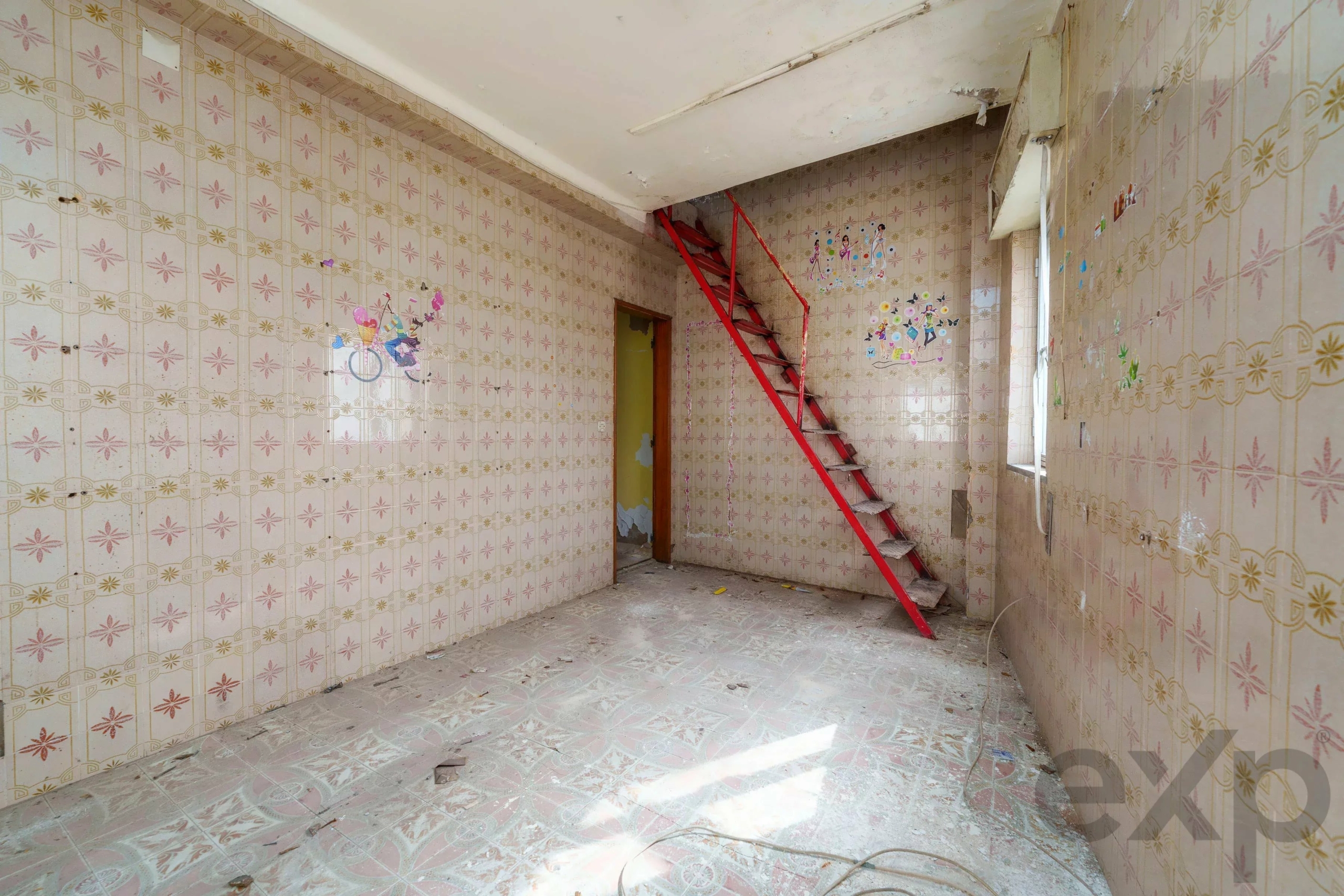 Abandoned tiled room with pink floral patterns, a bright red metal staircase, and peeling ceiling.