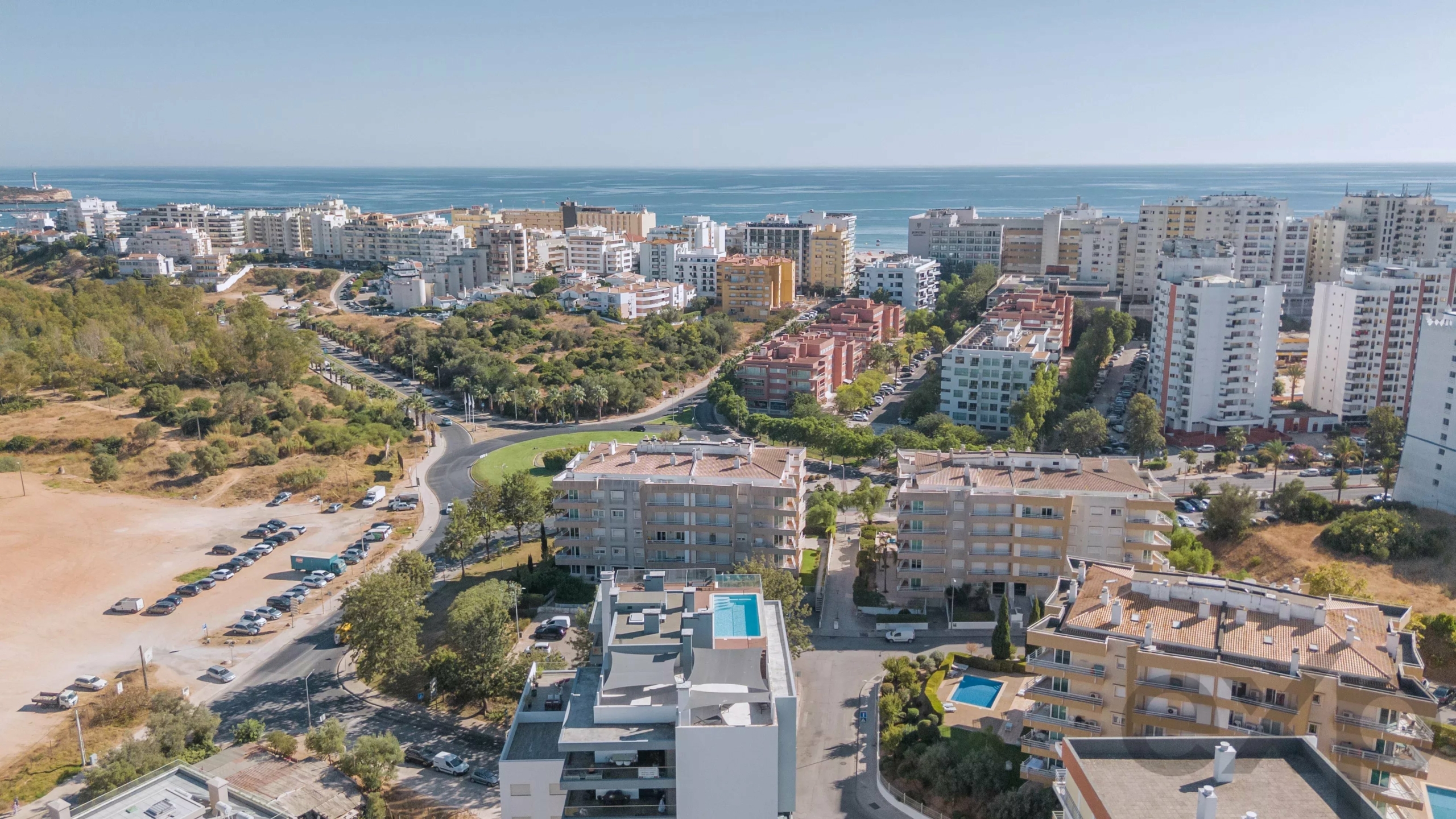Aerial view of a coastal city with high-rise buildings, roads, and a park near the ocean.