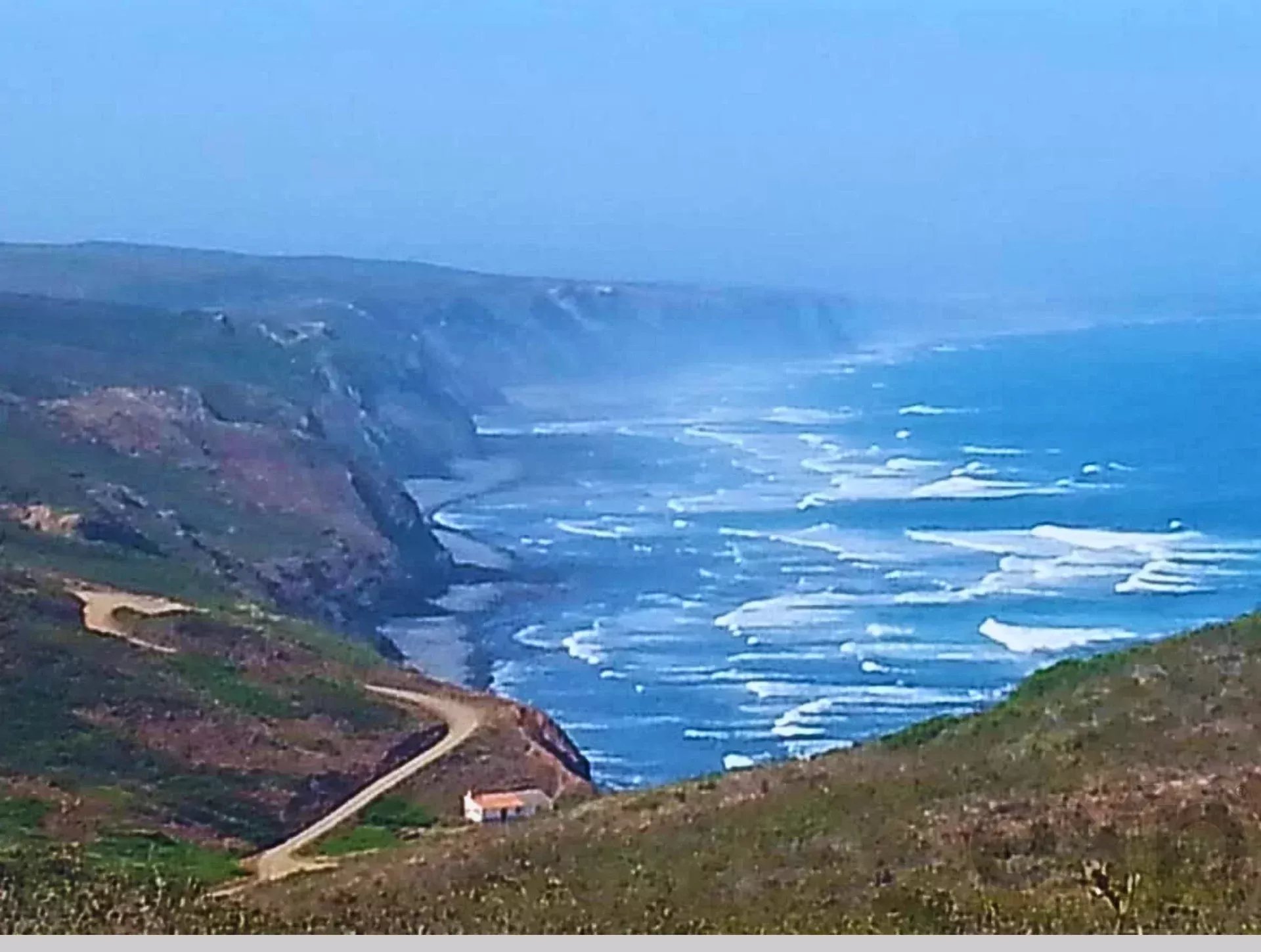 Coastal road winding along rugged cliffs above the blue ocean.