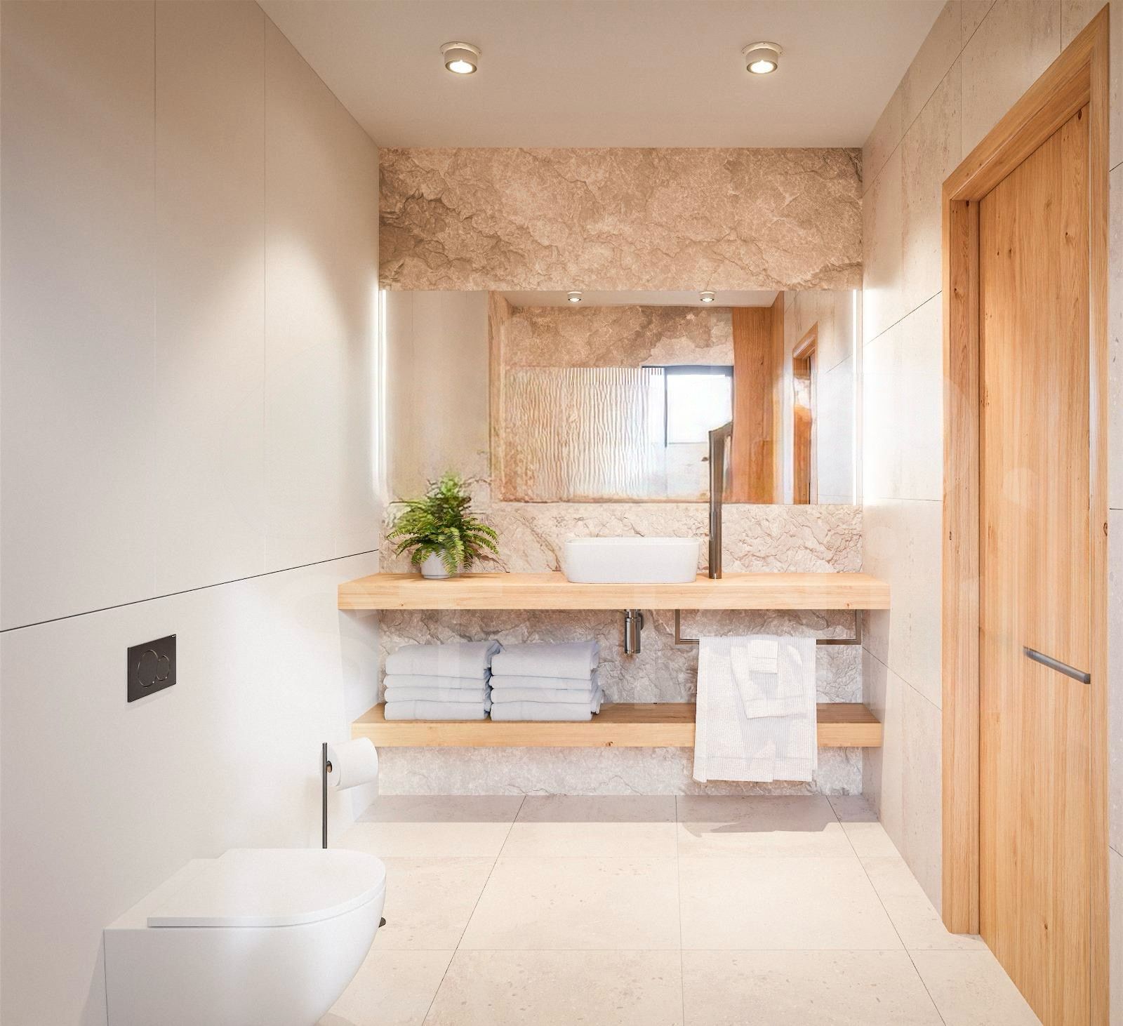 Floating wooden vanity with a white vessel sink, potted plant, and folded towels in a modern bathroom with stone wall accents and large mirror above.