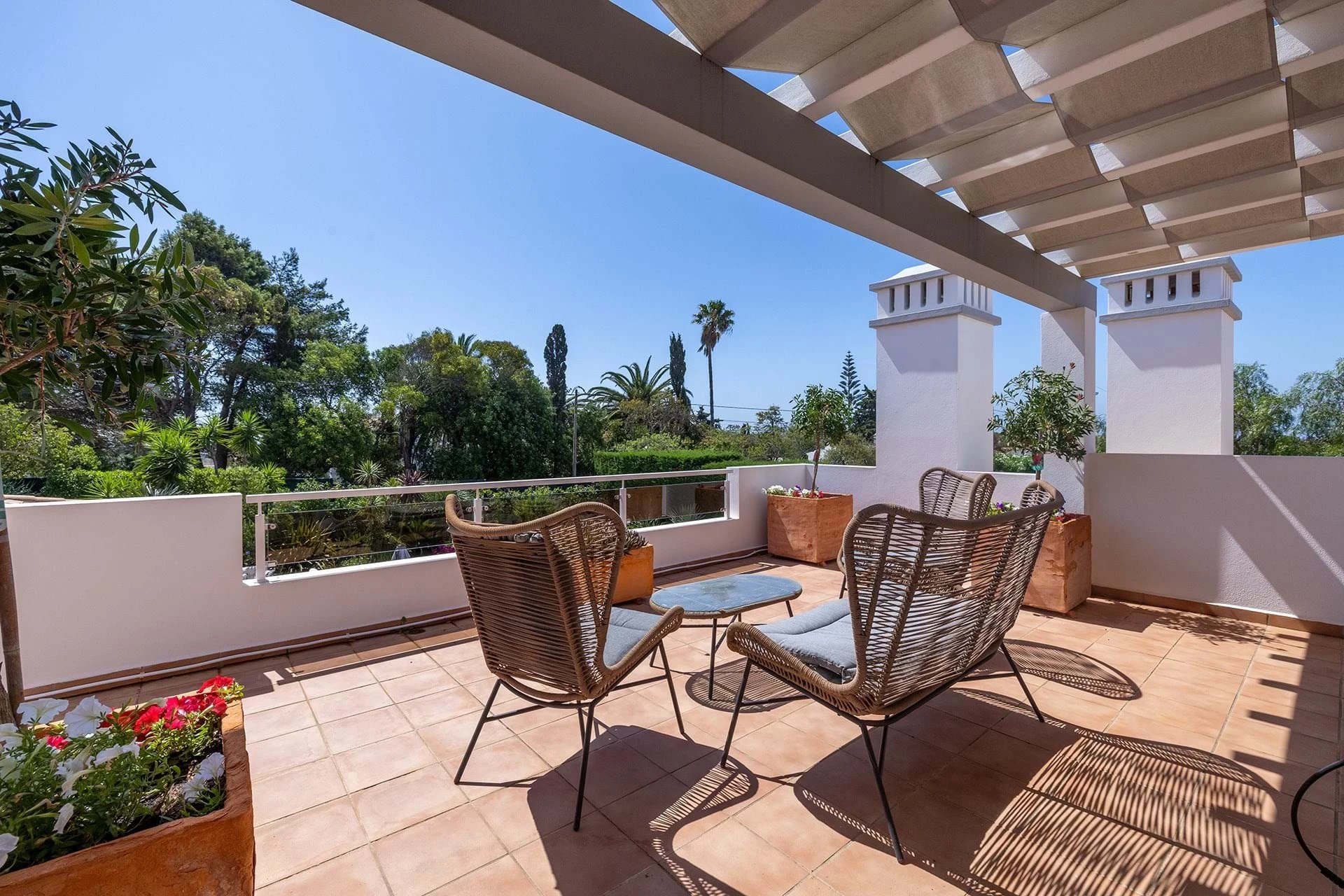 T5 Villa with pool in Ferrel 5mn from beach and Lagos centre – SunnySteve 33 Sunlit rooftop terrace with wicker chairs around a glass table, potted plants, and white columns under a slatted pergola.