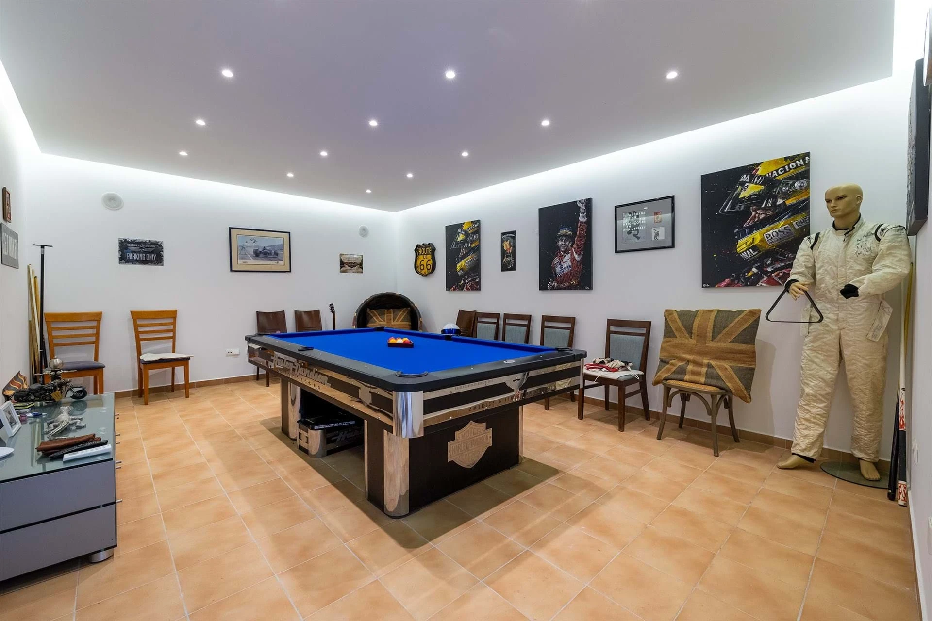 T5 Villa with pool in Ferrel 5mn from beach and Lagos centre – SunnySteve 40 Pool room with a blue-felt pool table, wooden chairs along the white wall, and framed posters. a life-size racing mannequin stands on the right.