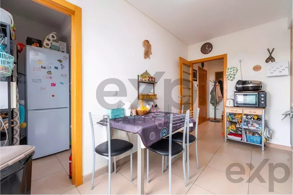 Small dining area with a purple-table and four metal chairs; fridge in an adjacent pantry and a microwave on a stand.
