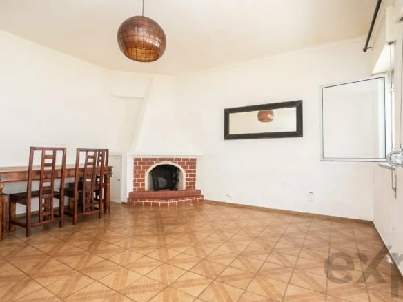Dining room interior with a wooden dining table and chairs, brick fireplace, and a large wall mirror on white walls.