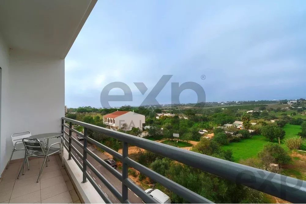 Balcony with a small metal table and two chairs overlooking a green suburban landscape.