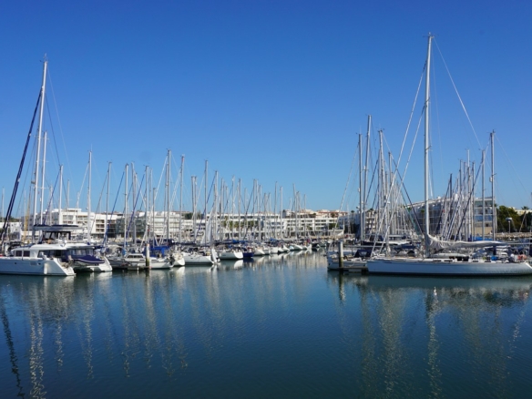 Yachts moored in Marina de Lagos on a clear day, with the apartment blocks and town of Lagos, Portugal behind
