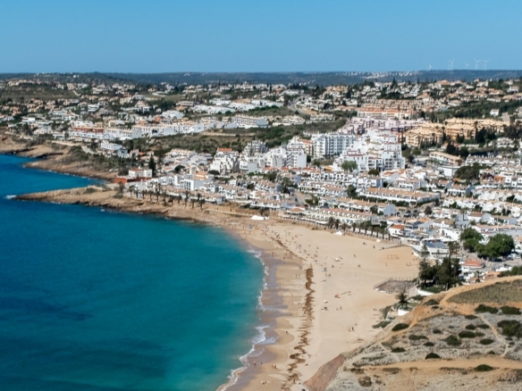 Aerial view of Praia da Luz, Portugal, showing the horseshoe bay, sandy beach and low-rise white village west of Lagos