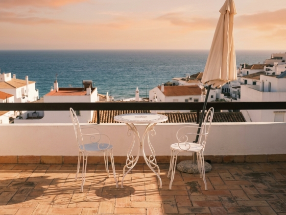 Terrace of a holiday apartment in Lagos, Algarve, overlooking terracotta rooftops and the Atlantic at sunset
