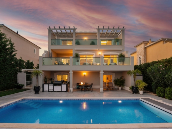 Three-storey villa with a lit swimming pool and terraces at dusk in the Algarve, the kind of home whose selling costs this 2026 guide breaks down