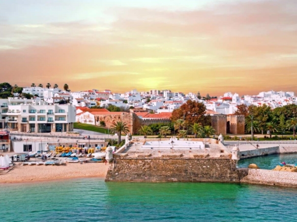 Sunset over Lagos, Portugal, with the Bandeira fort and holiday apartments on the waterfront, where holiday let rental yields average around 4.8% net in 2026